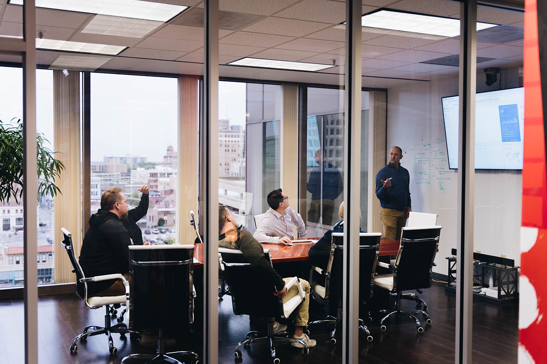 Matmon team in a Little Rock conference room working through a plan at the whiteboard, downtown out the window